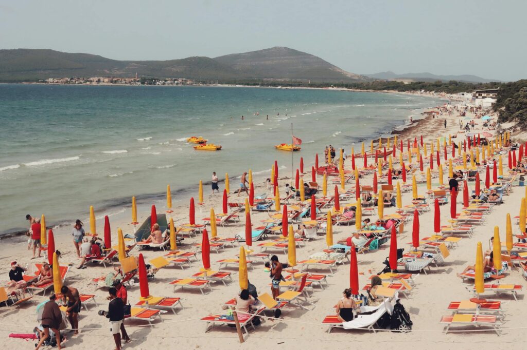 tourists sunbathing on yellow and red beach loungers